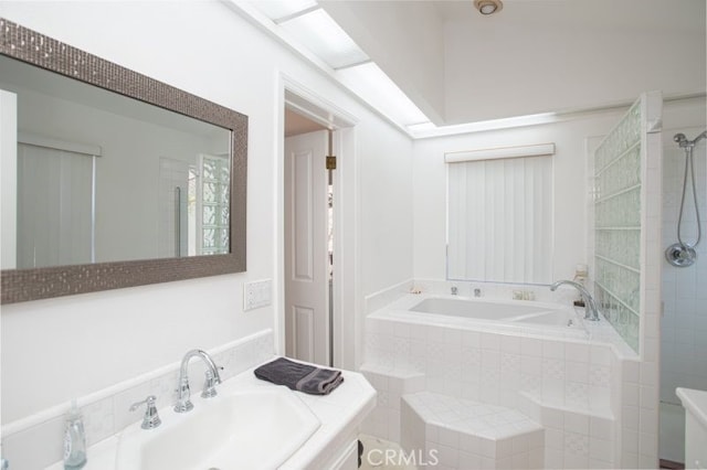 bathroom featuring a garden tub, tiled shower, and vanity