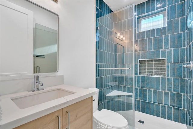 bathroom with tiled shower, vanity, and toilet