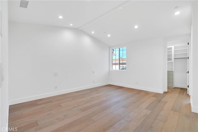 unfurnished room featuring lofted ceiling and light hardwood / wood-style floors