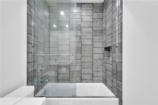 bathroom with toilet and combined bath / shower with glass door