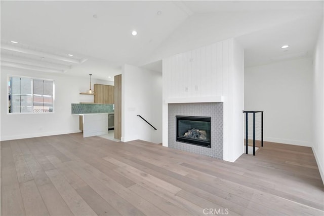 unfurnished living room with lofted ceiling, a fireplace, and light hardwood / wood-style flooring