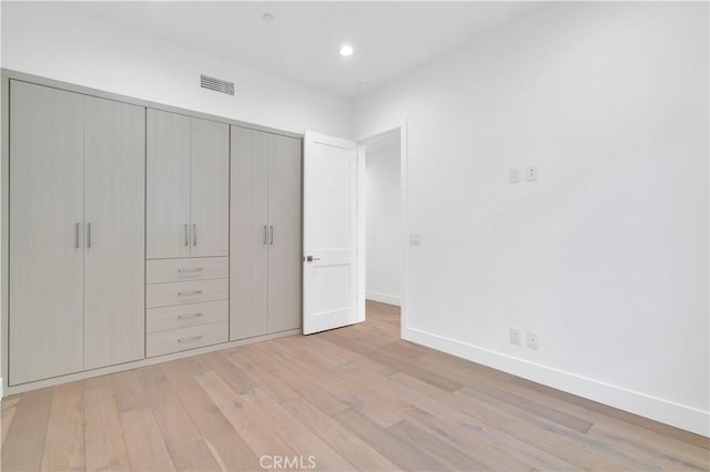 unfurnished bedroom with a closet and light wood-type flooring