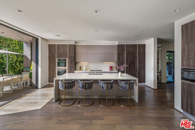 kitchen featuring a breakfast bar, dark hardwood / wood-style flooring, and an island with sink