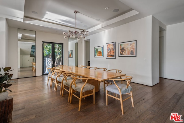 dining area featuring a tray ceiling, french doors, dark wood-type flooring, and an inviting chandelier