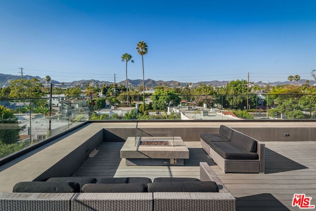 wooden terrace featuring a mountain view and an outdoor living space with a fire pit