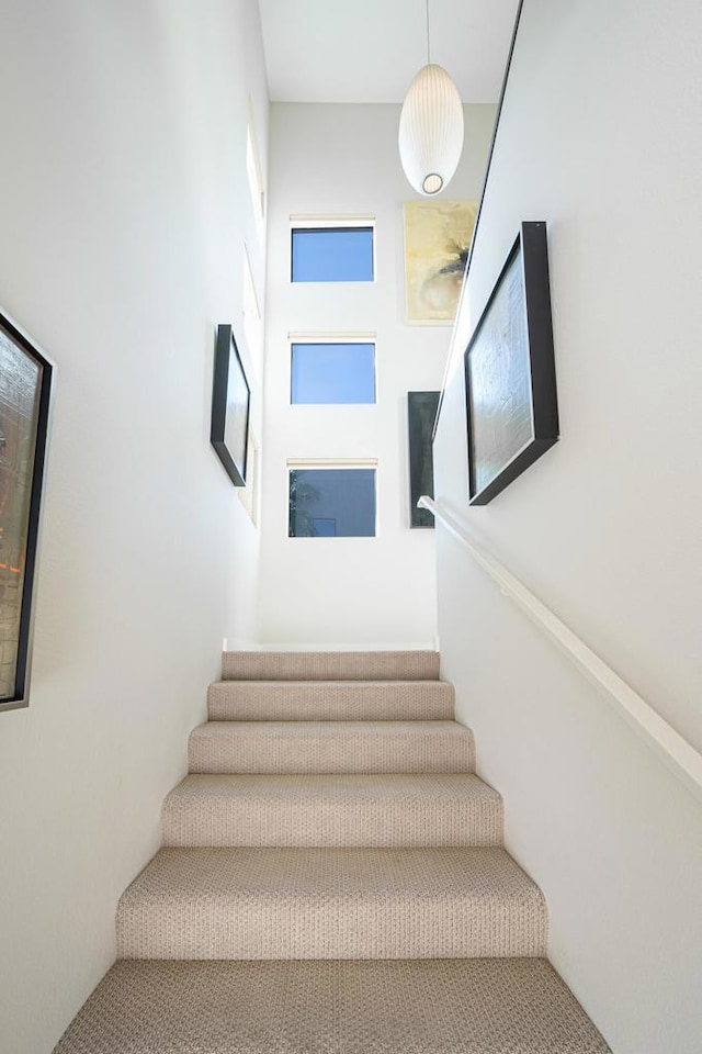 stairway featuring a towering ceiling