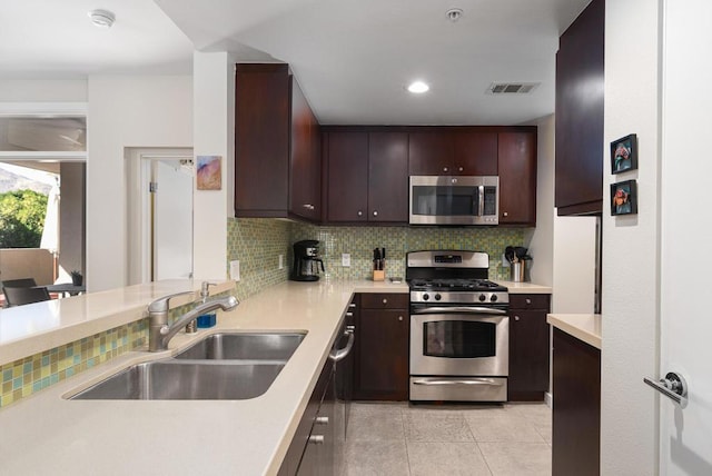 kitchen featuring dark brown cabinetry, sink, decorative backsplash, light tile patterned floors, and appliances with stainless steel finishes