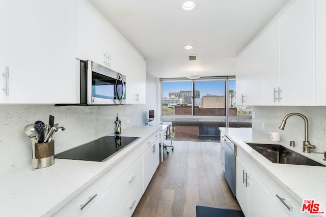 kitchen with appliances with stainless steel finishes, white cabinetry, and sink