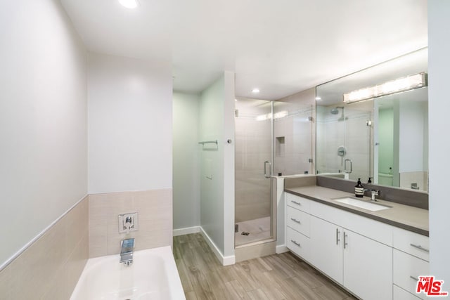 bathroom featuring hardwood / wood-style floors, vanity, and shower with separate bathtub