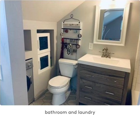 bathroom featuring stacked washer and clothes dryer, vanity, toilet, and lofted ceiling