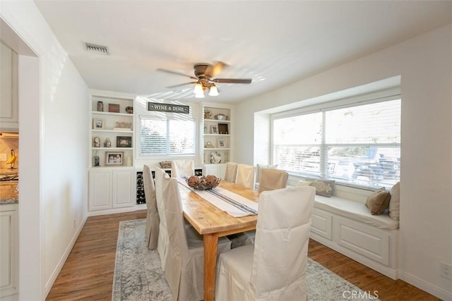 dining space with built in shelves, light hardwood / wood-style flooring, and ceiling fan