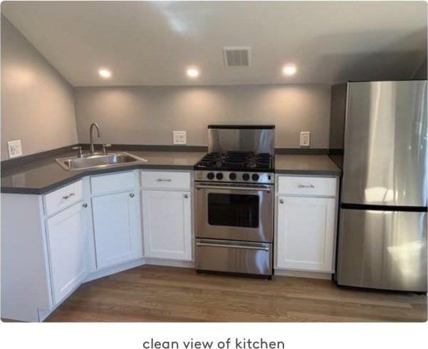 kitchen with white cabinetry, sink, stainless steel appliances, and wood-type flooring