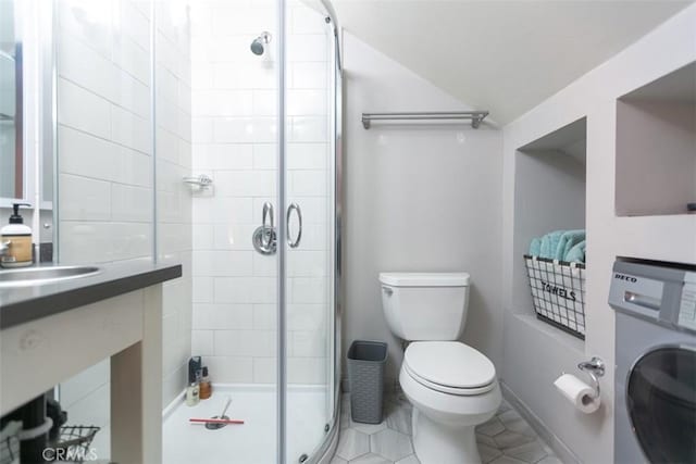 bathroom with washer / dryer, tile patterned flooring, toilet, a shower with door, and vanity