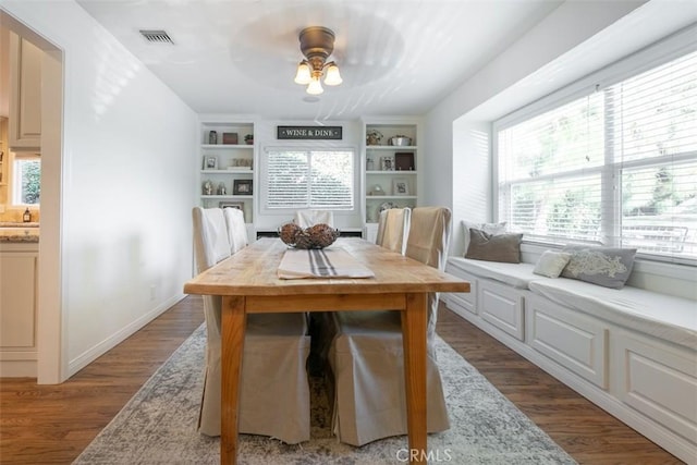 dining room featuring built in shelves, dark hardwood / wood-style floors, and ceiling fan