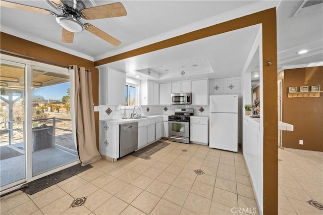 kitchen featuring backsplash, stainless steel appliances, a raised ceiling, sink, and white cabinets