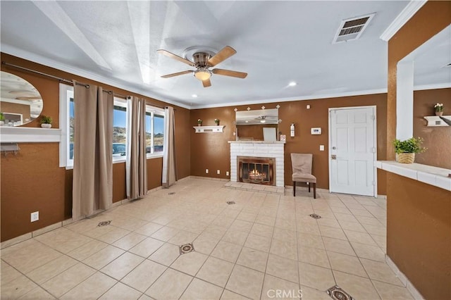 unfurnished living room with light tile patterned floors, a brick fireplace, ceiling fan, and ornamental molding