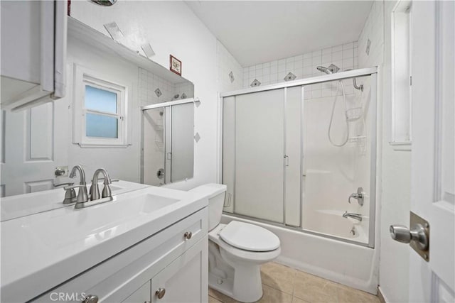 full bathroom with tile patterned floors, vanity, toilet, and bath / shower combo with glass door