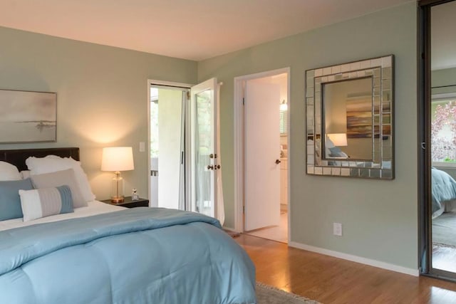 bedroom with hardwood / wood-style floors, access to outside, and multiple windows