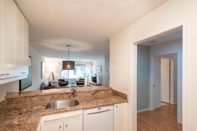 kitchen with pendant lighting, white dishwasher, sink, light stone countertops, and white cabinetry