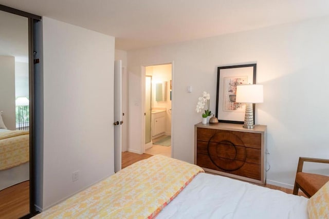 bedroom with light wood-type flooring and ensuite bath