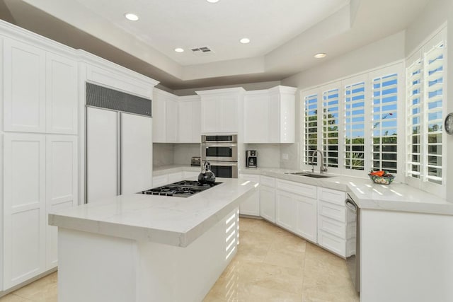 kitchen featuring a kitchen island, appliances with stainless steel finishes, white cabinetry, sink, and light stone counters