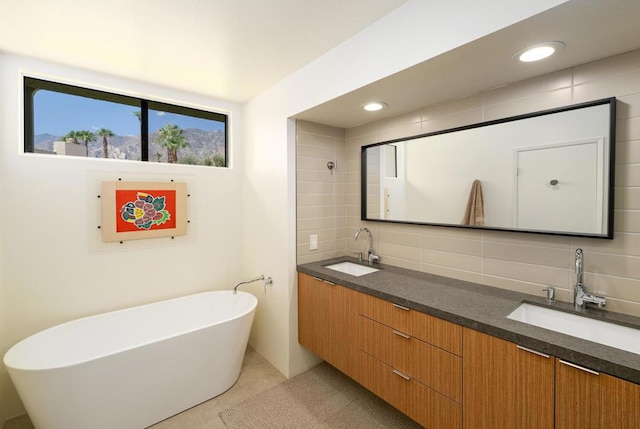 bathroom featuring tile patterned flooring, decorative backsplash, a bath, and vanity