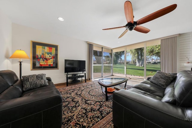 living room featuring hardwood / wood-style flooring, a wall of windows, and ceiling fan