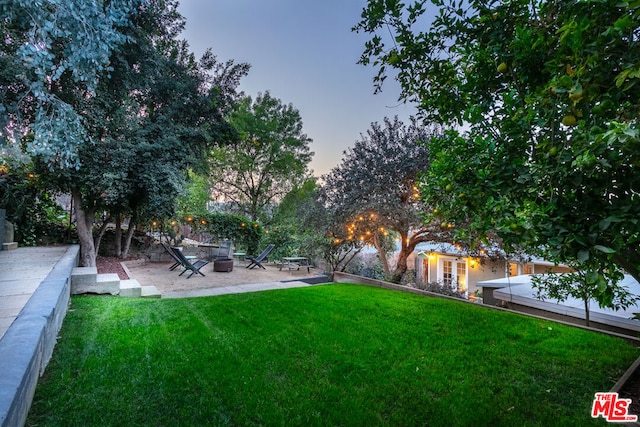 yard at dusk featuring a patio and an outdoor fire pit