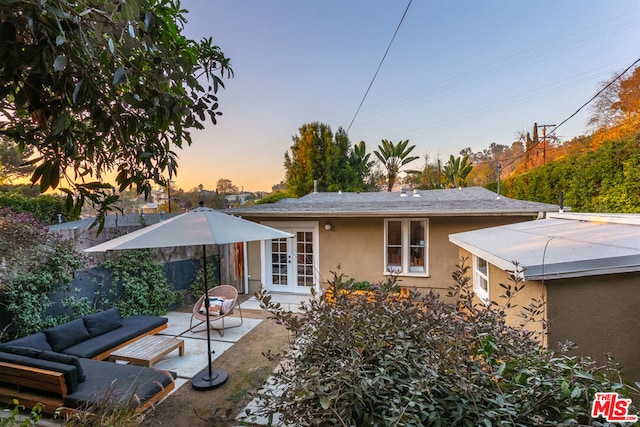 back house at dusk featuring french doors, a patio, and an outdoor hangout area