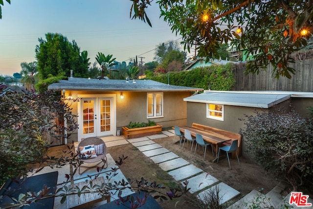 back house at dusk featuring french doors and a patio area