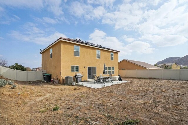 back of property with a patio area, central air condition unit, a fenced backyard, and stucco siding