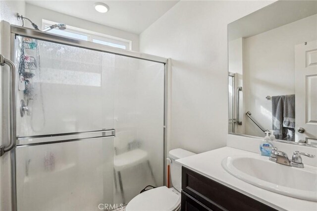 bathroom featuring toilet, a shower stall, and vanity