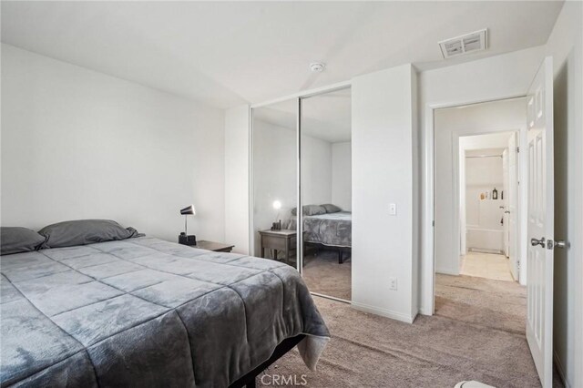 carpeted bedroom with visible vents and a closet