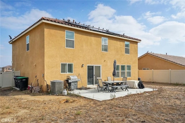 rear view of property with central AC, a patio area, roof mounted solar panels, and stucco siding