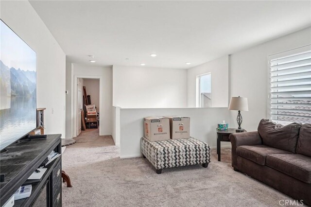 living area with light carpet and baseboards