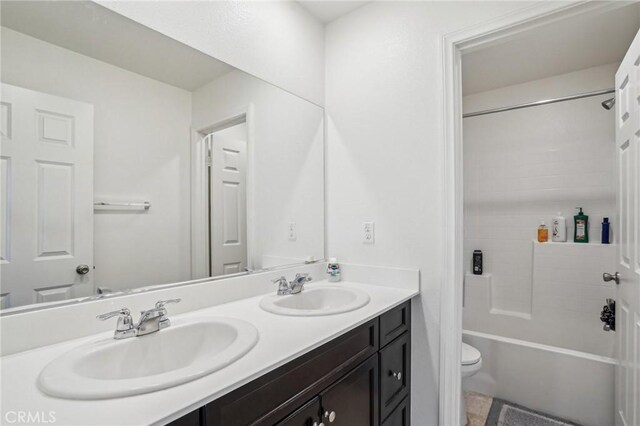 full bathroom featuring toilet, double vanity, a sink, and bathing tub / shower combination