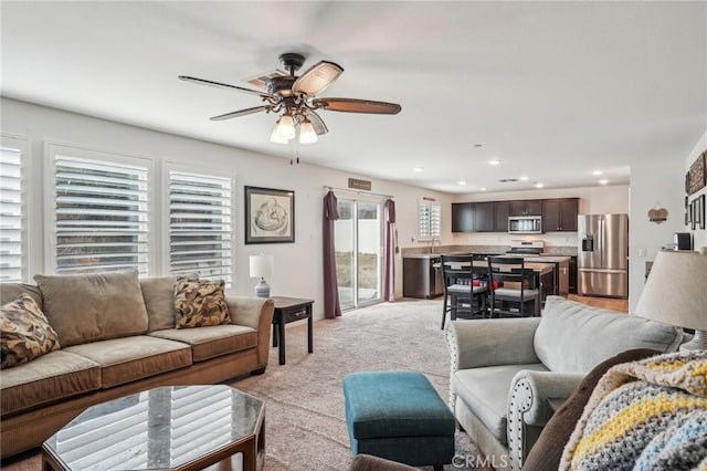 living area featuring recessed lighting, light colored carpet, and ceiling fan