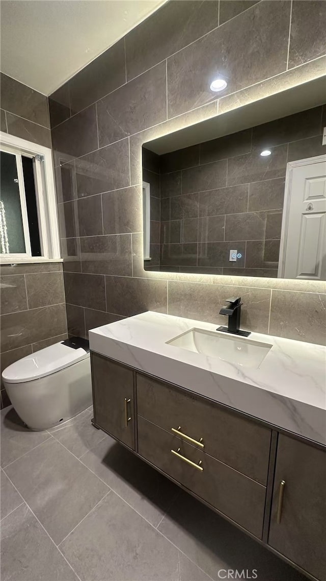 bathroom featuring tile walls, toilet, vanity, and tile patterned flooring