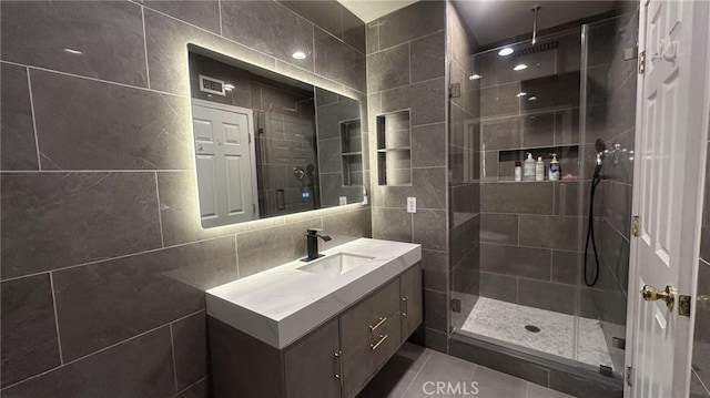 bathroom featuring an enclosed shower, vanity, tile walls, and tile patterned floors