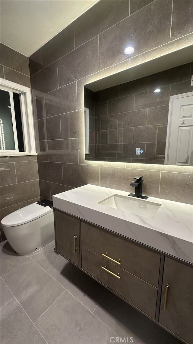 bathroom with toilet, tile walls, tile patterned floors, and vanity