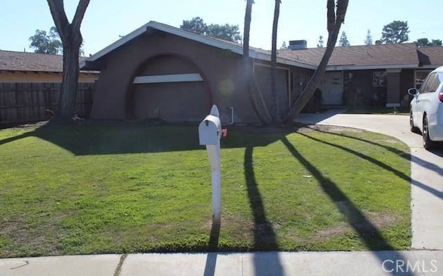 view of front of property featuring driveway, fence, and a front lawn