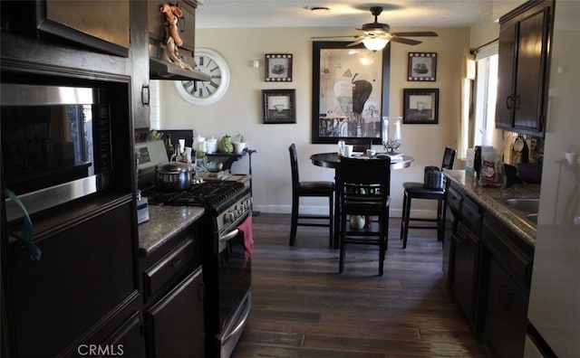 kitchen featuring appliances with stainless steel finishes, dark wood-type flooring, a ceiling fan, dark brown cabinets, and baseboards