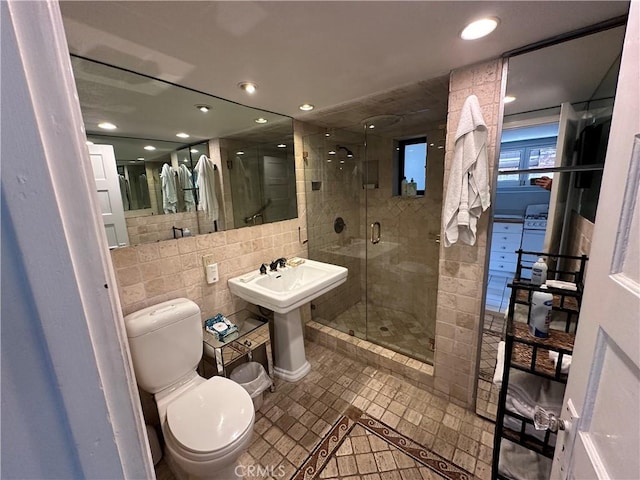 bathroom featuring sink, walk in shower, tile patterned flooring, toilet, and tile walls