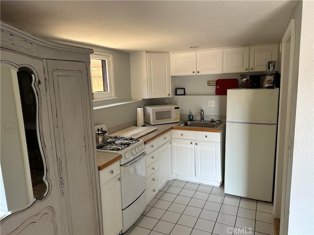 kitchen featuring white cabinets, light tile patterned floors, white appliances, and sink