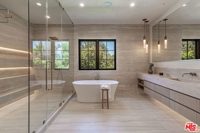 bathroom featuring separate shower and tub, tile patterned floors, vanity, and tile walls