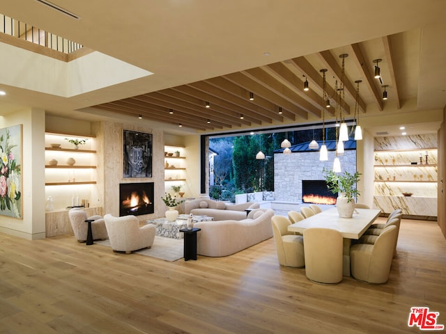 living room featuring a stone fireplace, built in shelves, and hardwood / wood-style flooring