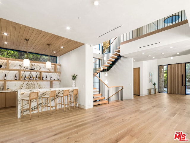 bar featuring a healthy amount of sunlight, wood ceiling, decorative light fixtures, and light wood-type flooring