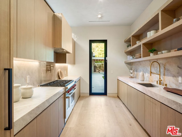 kitchen with decorative backsplash, sink, light brown cabinets, light hardwood / wood-style flooring, and range with two ovens