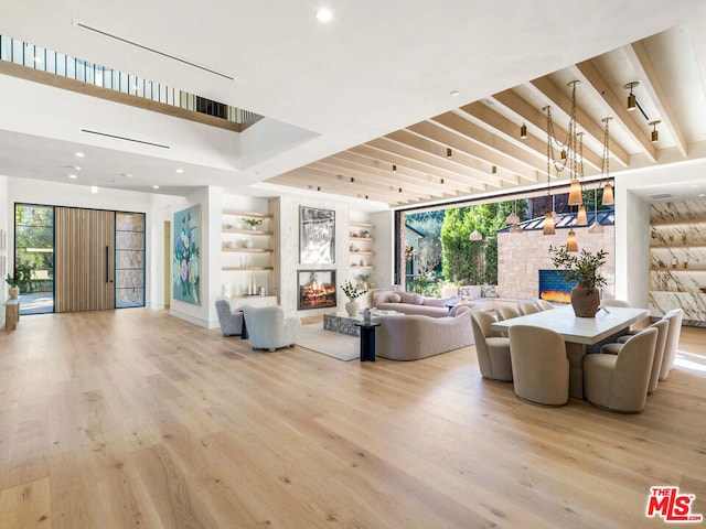 living room with a multi sided fireplace, light wood-type flooring, built in features, and a healthy amount of sunlight