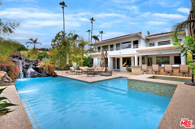 view of pool featuring outdoor lounge area, a patio area, a bar, and pool water feature